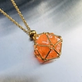 Golden mesh cage necklace featuring a faceted orange resin dice pendant on a slim chain - Gold Cage with Orange Dice