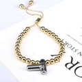 Detail of adjustable gold beaded bracelet featuring a polished silver 3D T-letter charm - Letter T