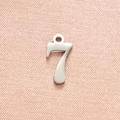 Macro view of polished stainless steel number 7 pendant on pink textured fabric background - Steel Color Number 7
