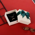 Caja de joyas beige con cinta verde y collar dorado sobre un fondo rojo festivo elegante - 7*7*3.5cm / Lazo Verde Oscuro
