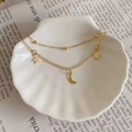 Double-layered gold moon and star pendant anklet displayed on a white shell plate - Gold (P311)