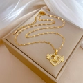 Detailaufnahme goldener Herz-Engelsflügel-Anhänger mit Mama-Gravur auf einer Schmuckschatulle - Goldenes 'mama' Engel Herz Stil (E128)