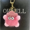 Close-up of pink fuzzy soot sprite keychain with crochet hat and golden metal clasp - Bright Pink