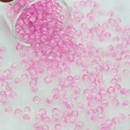 Macro shot of 6mm pink crackle glass beads pouring from a glass jar onto a soft white rug - 6mm / Pink
