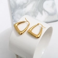 Close-up of gold water drop earrings with U-shaped flat hoop design on a ceramic cup - Triangle