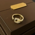 Makro-Detail des goldfarbenen Schloss-Rings mit Perlmutt-Inlay und funkelnden Zirkon-Steinen - Goldener Geometrischer Schnallenstil / Gold