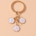 Detailed view of three pink and white soccer ball charms on a golden alloy keychain ring - Pink