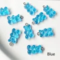 Detail view of blue resin gummy bear charms with silver jump rings for DIY jewelry making - Blue