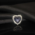 Macro shot of heart-shaped blue crystal with silver claw setting on black silk background - Ink Blue
