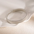 Gros plan d'un bracelet spiralé argenté texturé sur un plateau en céramique blanc - Bracelet élastique à texture fine argentée