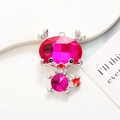 Macro shot of rose red dragon charm with pink gemstones and crystals on white marble - Silver Base Rose Red