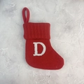 Red knit Christmas stocking with white letter D and hanging loop on marble surface - Letter D