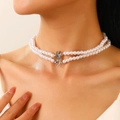 Collier double rang de perles blanches avec fermoir argenté sur un mannequin - Collier de Perles Artificielles Double Rang avec Noeud (9450)
