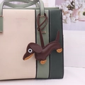 Chic green and cream leather handbag featuring a dark brown dachshund dog bag charm - Brown
