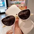 Occhiali da sole cat-eye bianco sporco con lenti scure tenuti da una modella - Bianco latte