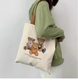 Detailed side view of a large cream canvas tote bag with cute bear prints on model - Three Bears Beige