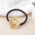 Detailed view of black elastic hair tie featuring a polished gold swirl metal ornament - Gold Chain Circle