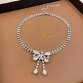 Detailed macro view of silver bow pendant with double-row rhinestones and tassels - Double Row Rhinestone Bowknot Tassel Necklace / Silver