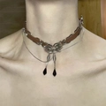 Détail du ras-du-cou en cuir marron avec pendentif nœud argenté et cristaux noirs - Chaîne de Clavicule Papillon X3724