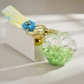 Close-up of cat paw acrylic keychain with green liquid filling and yellow silicone strap - Quicksand Luminous Style / Green
