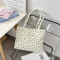Close-up of quilted heart pattern tote bag with brand label on a stylish chair - Mini Black Hearts