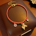 Dettaglio del bracciale cordino rosso intrecciato con ciondolo pony dorato e moneta chic - Oro e Rosso (Placcato oro 18K Cavallo)