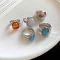 Detail of silver geometric rings with amber and blue gemstones on a white ceramic plate - Five-Piece Set / Silver