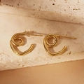Detailed view of golden spiral geometric stud earrings on beige natural stone and silk - Spiral Geometric Style