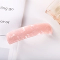 Macro shot of pink acetate hair clip with marble texture detail on white book page - 13# Spring Clip (Pink Marble)