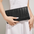 Dettaglio di una pochette da sera plissettata nera con patta rettangolare tenuta da modella - Nero