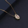 Close-up of a gold teardrop pendant with champagne zircon and white crystals on black leather - Orange