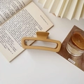 Detail of matte mustard yellow rectangular hair claw clip on an open book in a soft setting - Matte Large Square Milk Tea