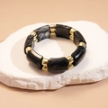 Nahaufnahme von geometrischen Marmor-Resin-Perlen und goldenen Distanzstücken auf Naturstein - Schwarzes Marmormuster (HB4173)