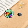 Cute green cartoon frog enamel pin holding a rainbow heart on an orange surface - Alloy / Frog Holding Heart
