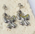 Detailed view of polished silver bow stud earrings with heart center on stone background - Bowknot Heart Studs / Silver