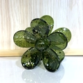 Détail d'une pince à cheveux fleur vert foncé translucide avec paillettes dorées et ressort - Vert