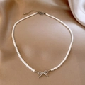 Elegante silberne Perlenkette mit diamantbesetztem Schleifenanhänger auf Champagner-Seide - Silberne Schleife Perlenkette Halskette