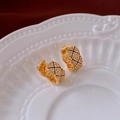Detailed view of C-shaped gold earrings with black quilted pattern and sparkling crystals - Quilted Zirconia Style