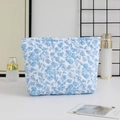 Close-up of blue floral quilted makeup bag with zipper closure and diamond stitching - Large Capacity / White with Blue Flowers