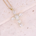 Dettaglio della collana in rame dorato con ciondolo a croce in zircone su pietra beige - Bianco