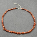 Macro detail of natural red stone beads on a stainless steel necklace with lobster clasp - Southern Red Agate