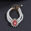 Close-up of triple-layer pearl bracelet with red oval gemstone and vintage gold clasp - Pink Main Stone Multi-layer Pearl Bracelet