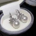 Vista macro di orecchini di perle bianche con montatura a fiore in argento e zirconi - Argento & Bianco (Silver Earring Post)