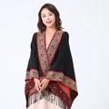 Black knit poncho with red paisley trim and decorative tassels shown on a model - Black/Border Paisley