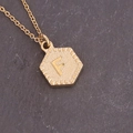 Macro shot of gold hexagon necklace pendant featuring embossed letter F on a dark slate surface - Letter F (6#F)