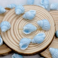 Detailed view of blue ceramic shell beads with white stripes on wooden display - Light Lake Blue