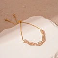 Vista detallada de pulsera ajustable dorada con circonitas rectangulares y diseño cruzado - Estilo de Circón de Torsión / Dorado
