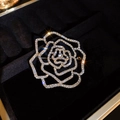 Détail macro d'une broche camélia évidée dorée scintillante sertie de strass - Doré