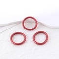 Tre vivaci bracciali rigidi rossi metallizzati glitterati su superficie bianca minimalista - Anelli in metallo rosso con trama seta 3 pezzi (50015 (Anello))