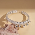 Dettaglio del bracciale aperto in argento con piccoli campanelli su una base di pietra - Campana d'argento